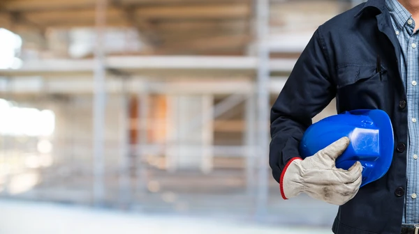 Chantier de construction ext&eacute;rieur avec contrema&icirc;tre en tenue de s&eacute;curit&eacute; consultant une tablette num&eacute;rique