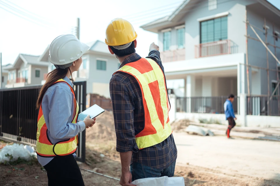 Chantier de construction extérieur avec charpentier travaillant sur une structure de toit en bois