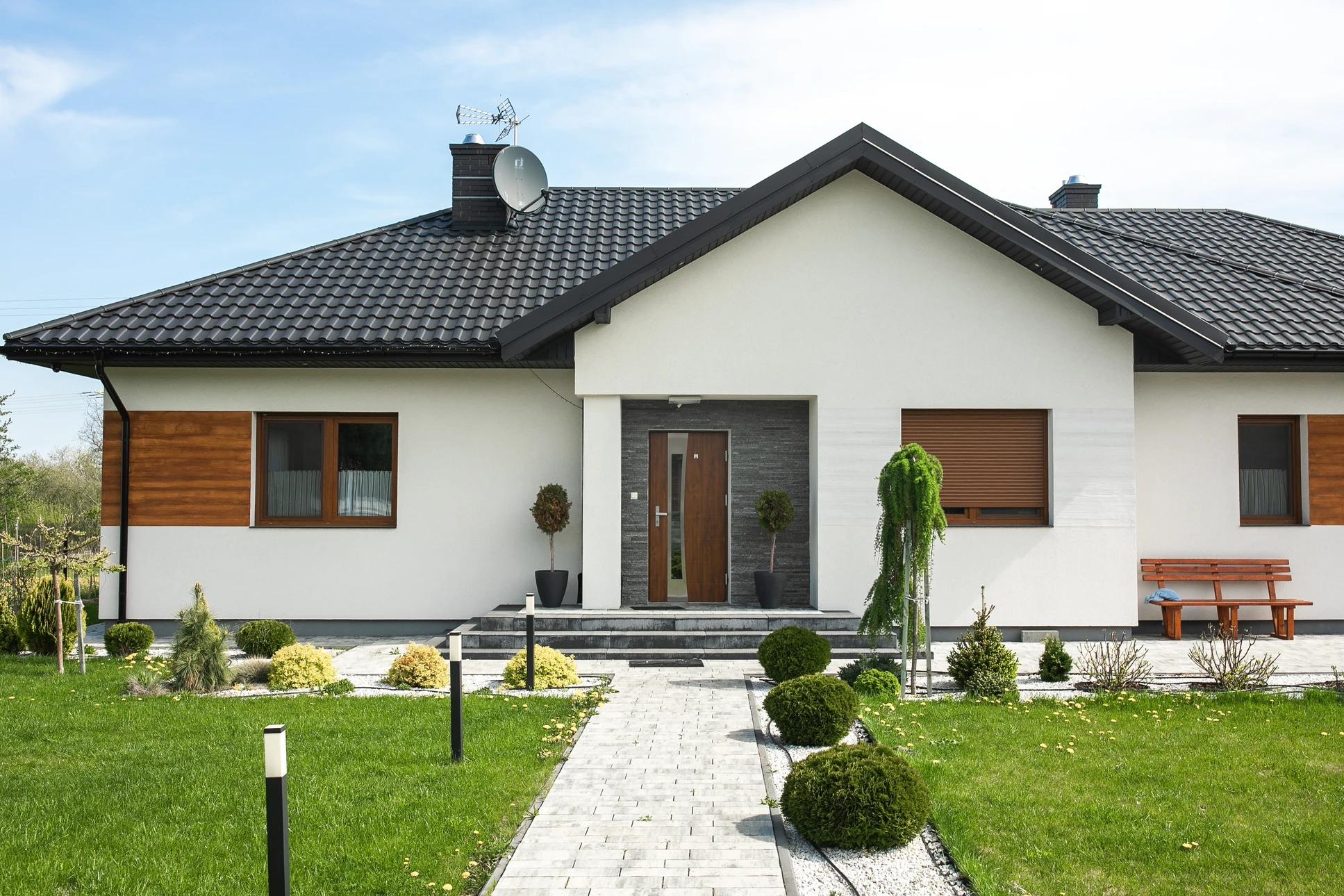 Photographe aérienne ou vue d'ensemble d'un chantier de construction en cours de travaux, montrant des ouvriers en gilets de sécurité coordonnant différents postes de travail (terrassement, maçonnerie, charpente, menuiseries visibles), avec des plans architecturaux ou des documents de suivi sur le terrain. L'image doit transmettre la notion de pilotage rigoureux, de coordination entre les différents corps de métier, et d'organisation professionnelle d'un projet de construction.