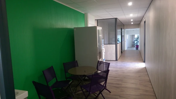 Réunion de travail dans un bureau moderne avec trois professionnels en discussion debout près d'une fenêtre